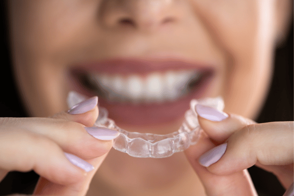 A girl holding clear aligners