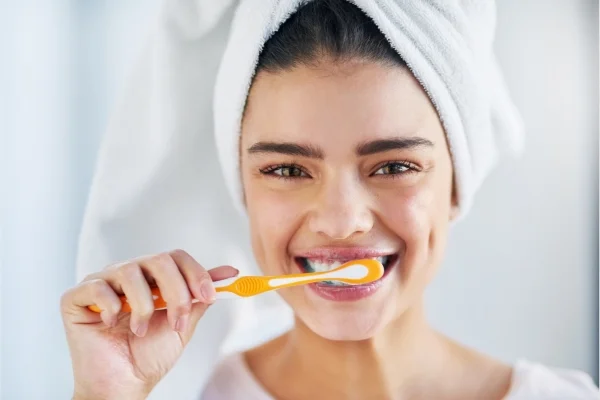 A woman brushing her teeth as part of her oral hygiene routine