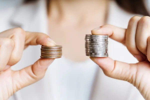 A woman holding two piles of coins to compare prices between ALIGNERCO and CandidPro