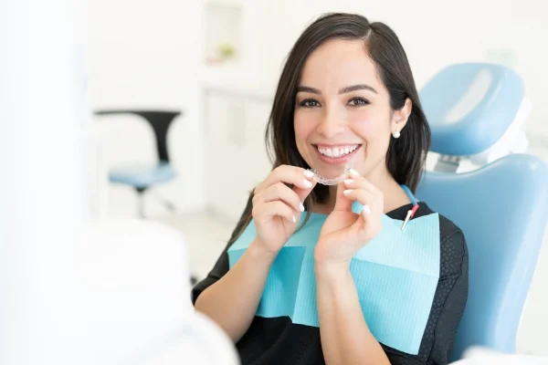 A woman smiling and wearing clear aligners